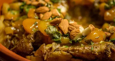 Chicken tagine with apricots and fresh herbs on a wooden table