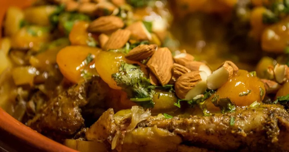 Chicken tagine with apricots and fresh herbs on a wooden table