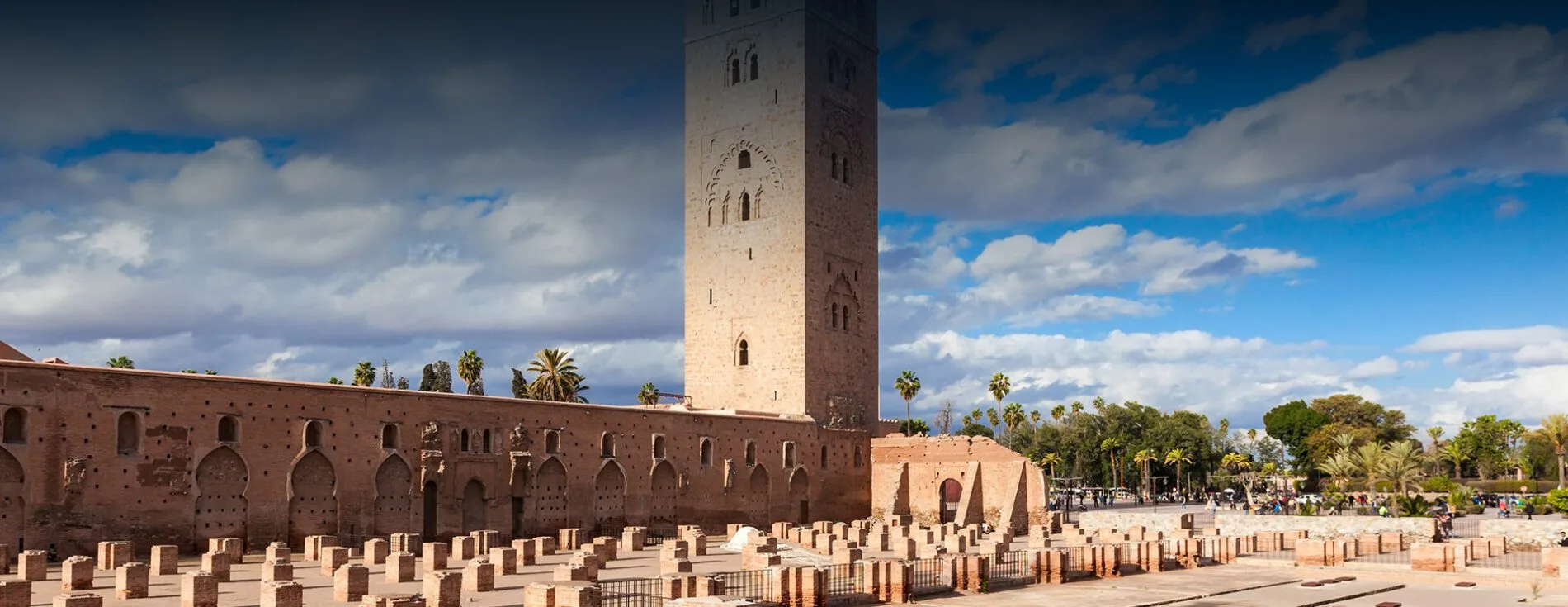 Koutoubia Mosque minaret and brick ruins under a cloudy Marrakech sky