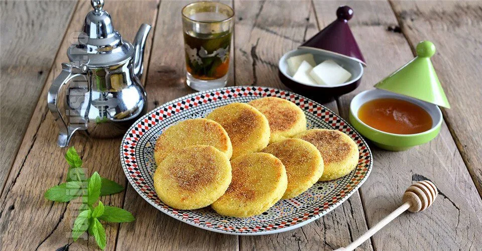 Silver teapot, mint tea and harcha flatbreads on a wooden table