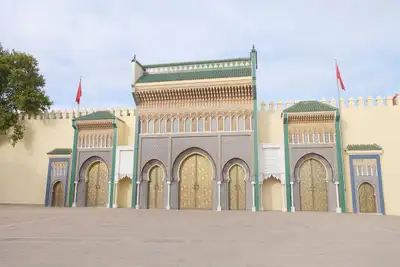 Golden brass doors and blue zellige of the Royal Palace gates in Fez
