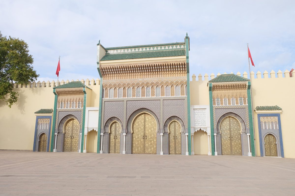 Golden brass doors and blue zellige of the Royal Palace gates in Fez