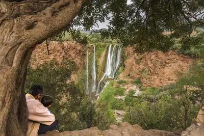 Travellers overlooking the cascading Ouzoud Falls from a cliffside
