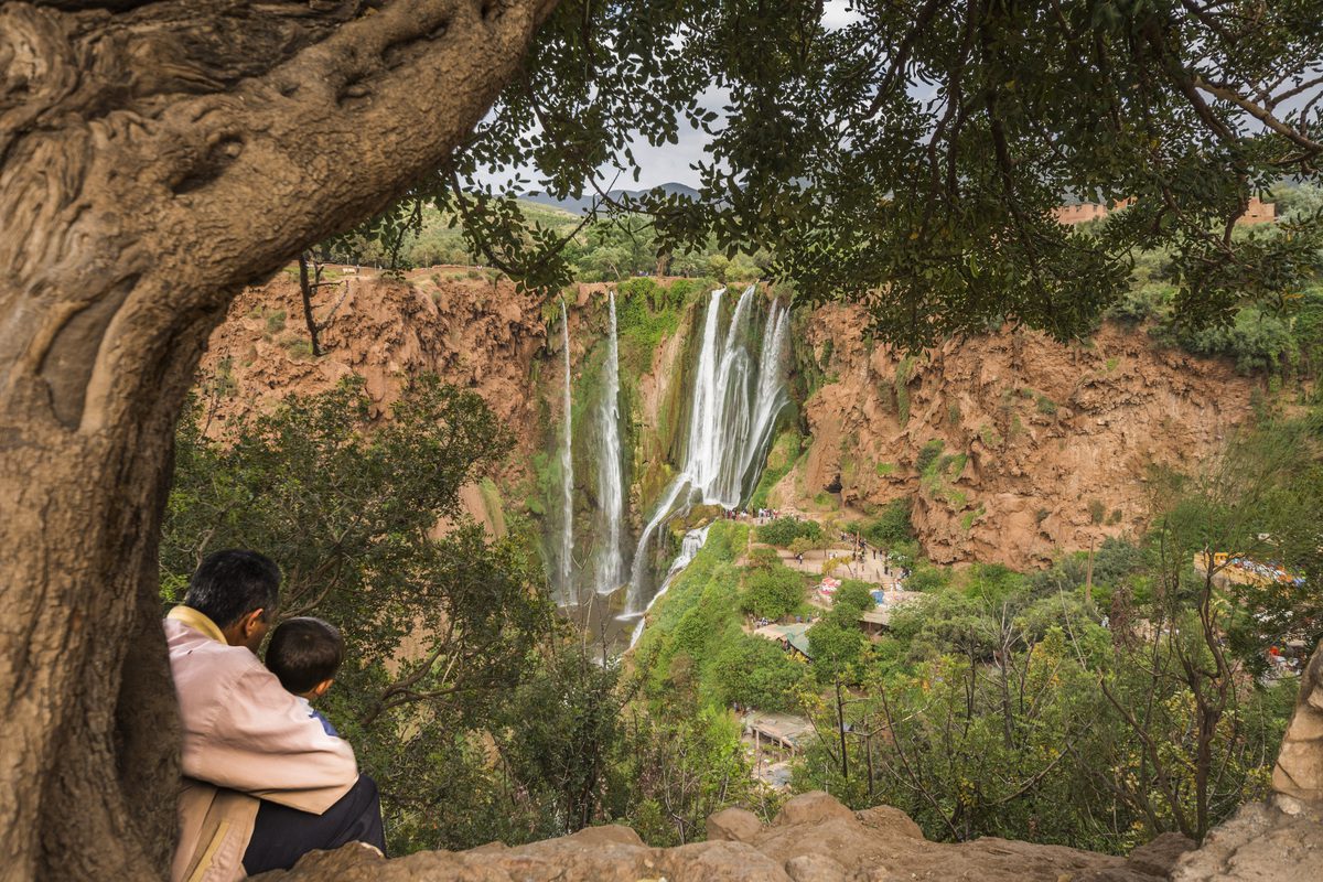 Travellers overlooking the cascading Ouzoud Falls from a cliffside