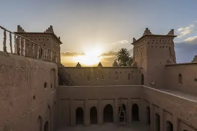 Mud-brick kasbah courtyard towers lit by a desert sunset