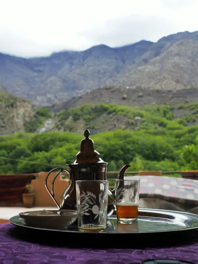 Glasses of mint tea served outdoors against Atlas mountain views