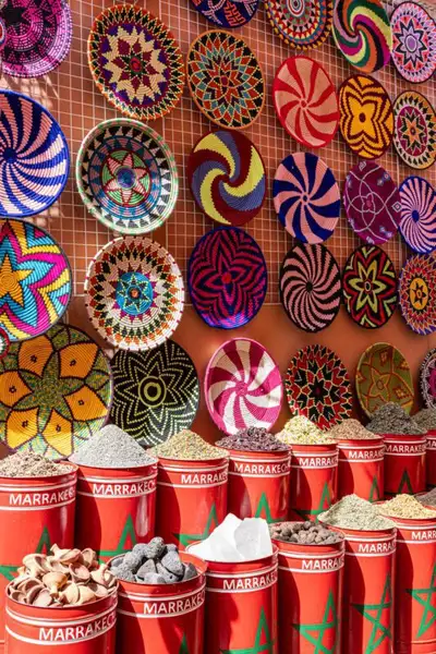 Market stall of patterned woven baskets above red Marrakech spice bins