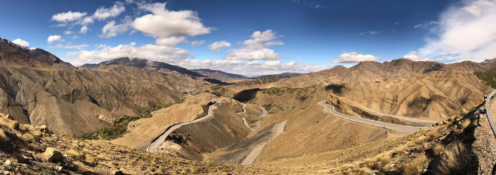 Hairpin mountain road winding through arid Atlas peaks under a bright blue sky