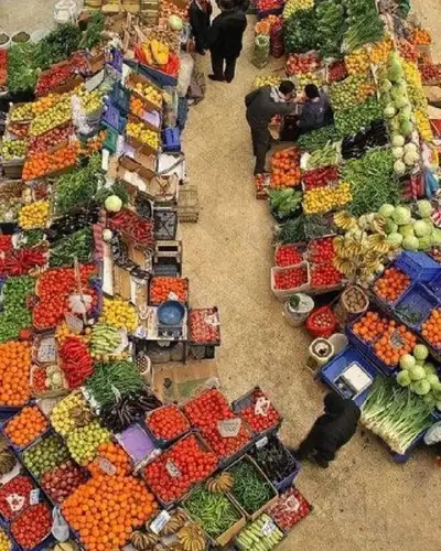 Overhead view of a produce market aisle lined with crates of tomatoes, citrus and greens
