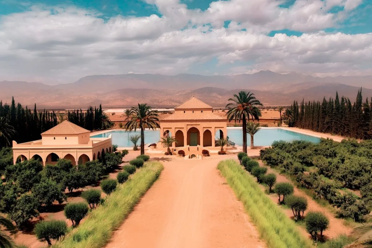 Palm-lined villa and turquoise pool set against the Atlas Mountains