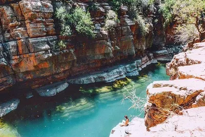 Turquoise natural rock pool enclosed by layered orange cliffs in Paradise Valley