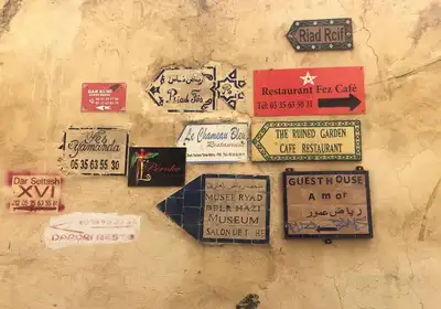 Hand-painted signs for riads, guesthouses and restaurants clustered on a medina wall in Fez